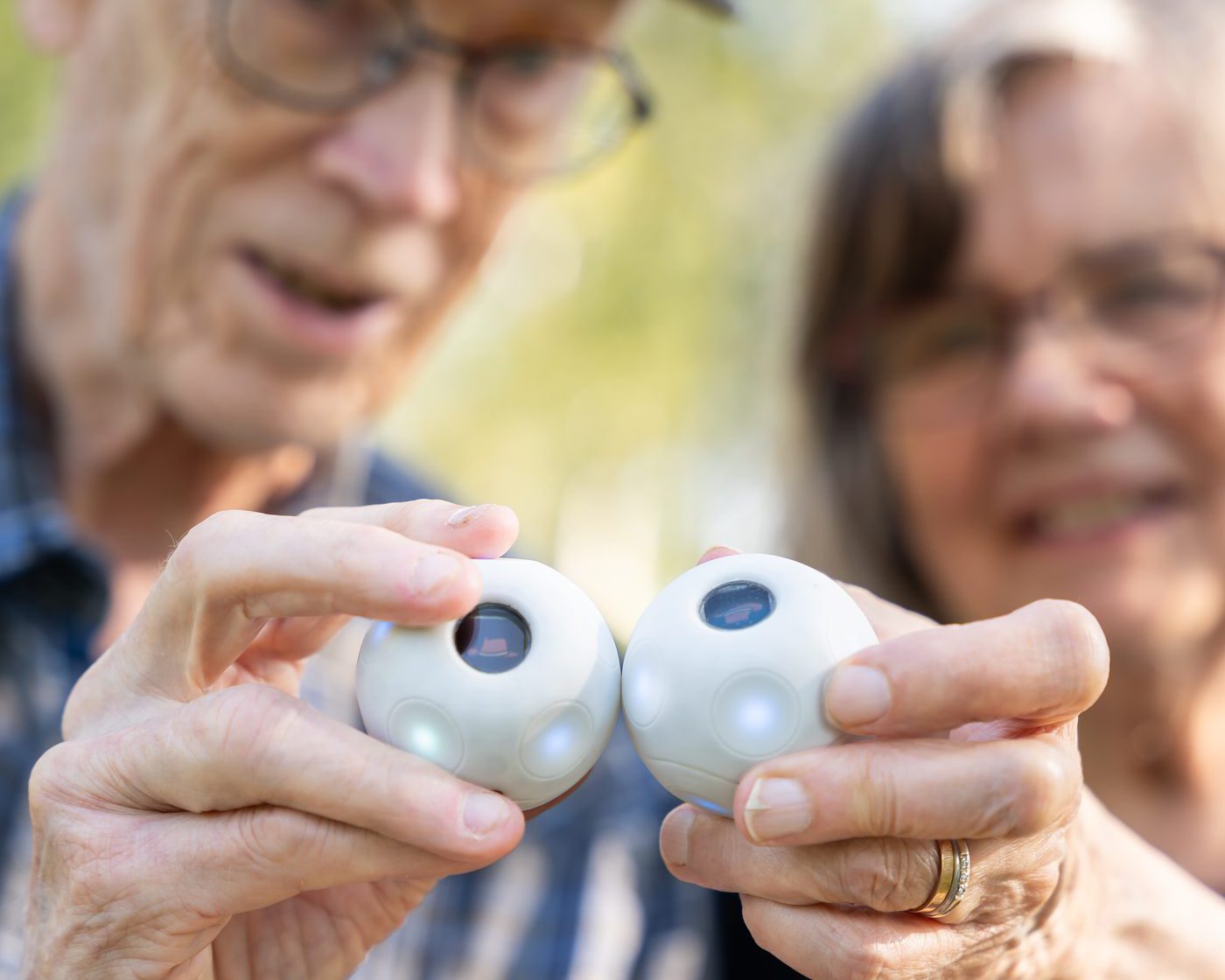 An older couple smiling as they hold up two PALL0 balls