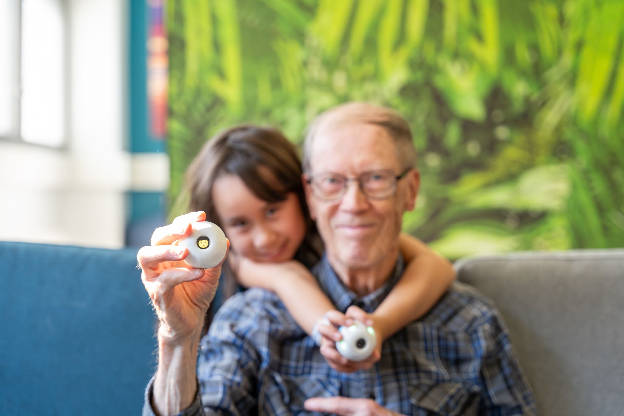A child and an older man each holding up a PALL0 ball